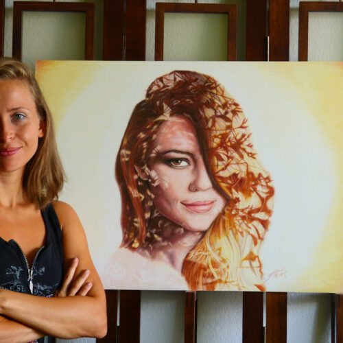 2016 photo showing the artist standing proudly next to a realistic colored pencil drawing. The artwork features a double-exposure style portrait, seamlessly blending two vibrant images together.